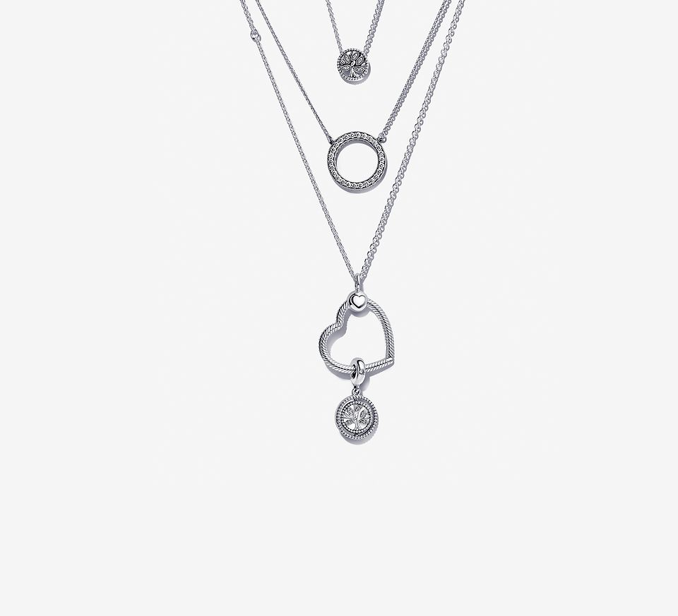 Drei Halsketten im Lagenlook, darunter eine Halskette mit Strahlenkranz, eine Pandora O Pendant Halskette und eine Herzanhänger-Halskette mit einem Charm