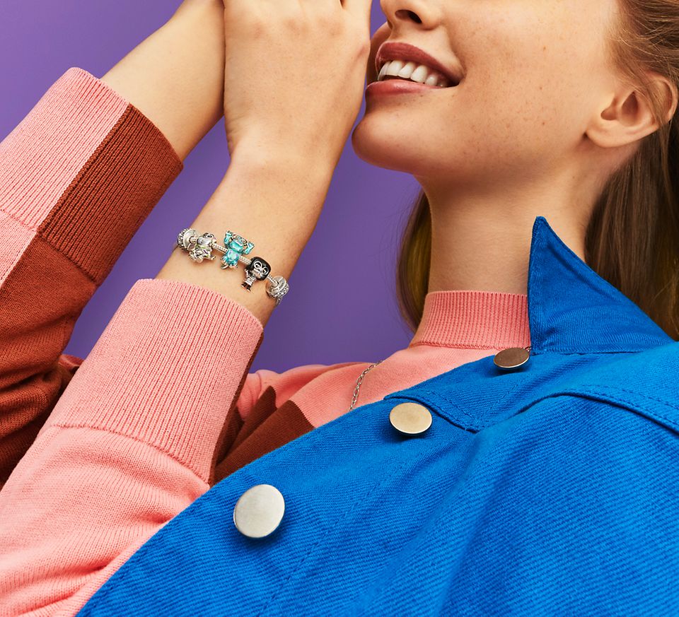 Une femme portant un bracelet en argent avec des charms de la collection Pixar