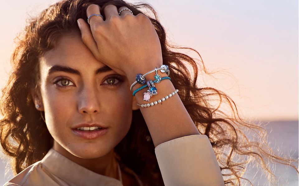 Woman wears 3 Pandora Moments bracelets with pearls and blue charms