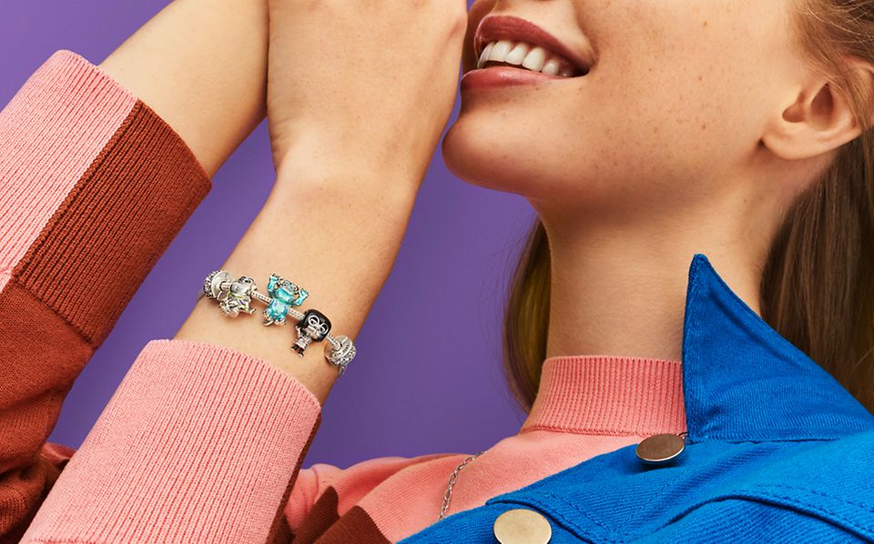 Kobieta nosząca srebrną bransoletkę z charmsami z kolekcji Pixar