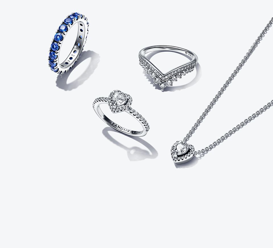 Selezione di gioielli della collezione Timeless. Due anelli, orecchini e collana con zirconi, e un anello con cristalli blu.