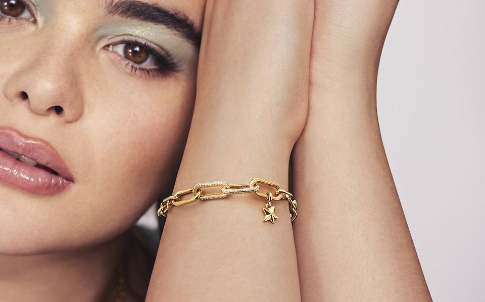 Personne portant un bracelet link Pandora ME avec des charms en argent 925/1000e doré à l'or