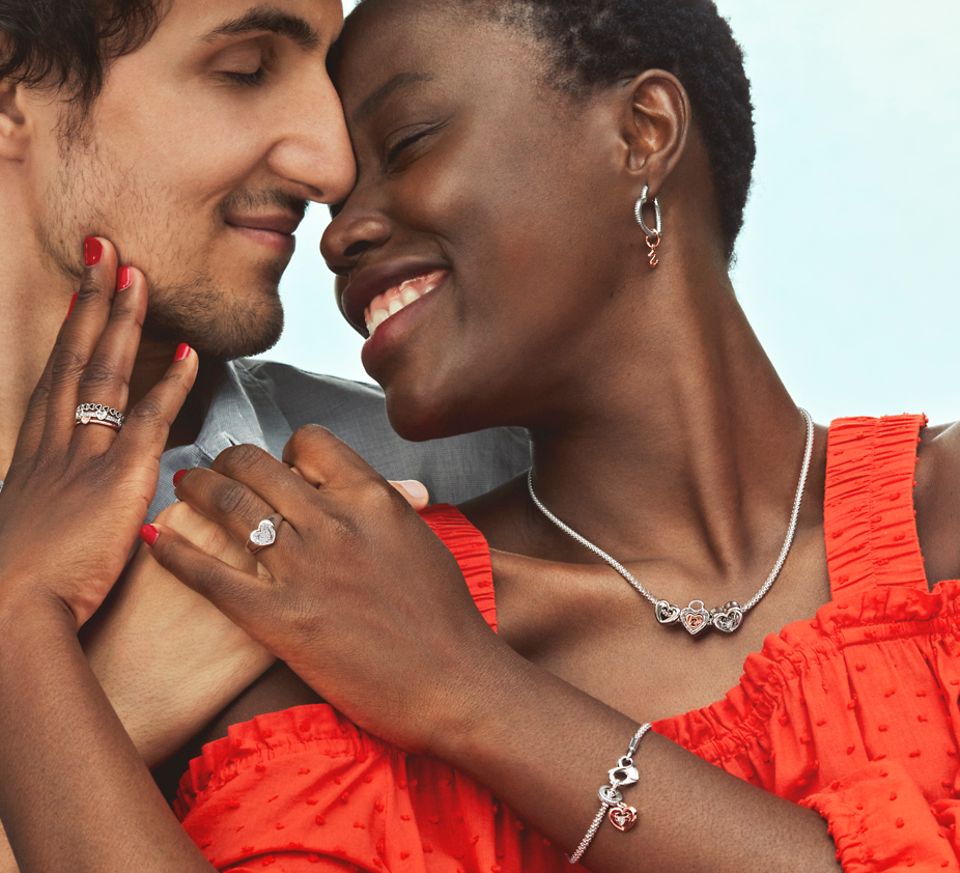 smiling women wearing bracelet, necklace, and earrings hugs a man