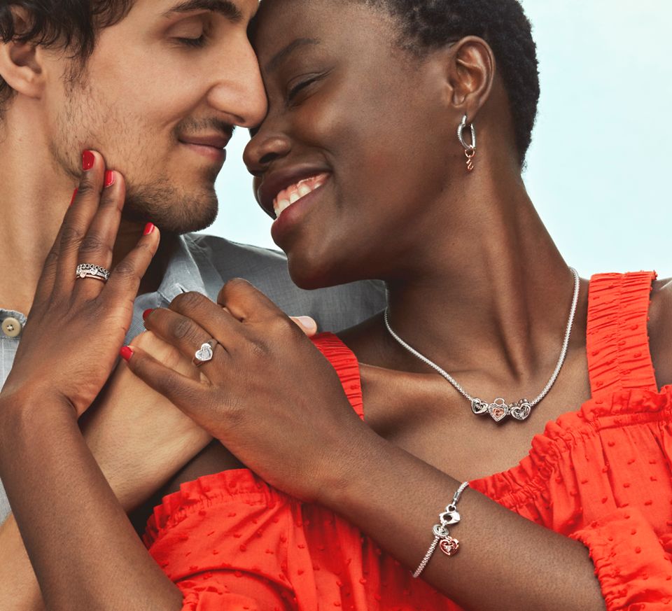 smiling women wearing bracelet, necklace, and earrings hugs a man