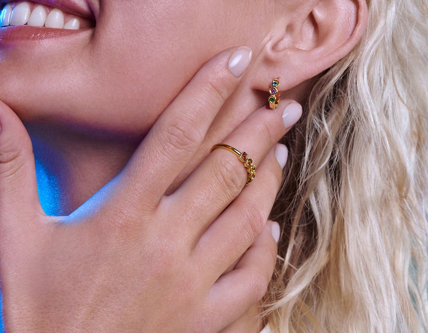 Modelka nosząca złote pierścionek i kolczyki z kamieniami nieskończoności Marvel x Pandora