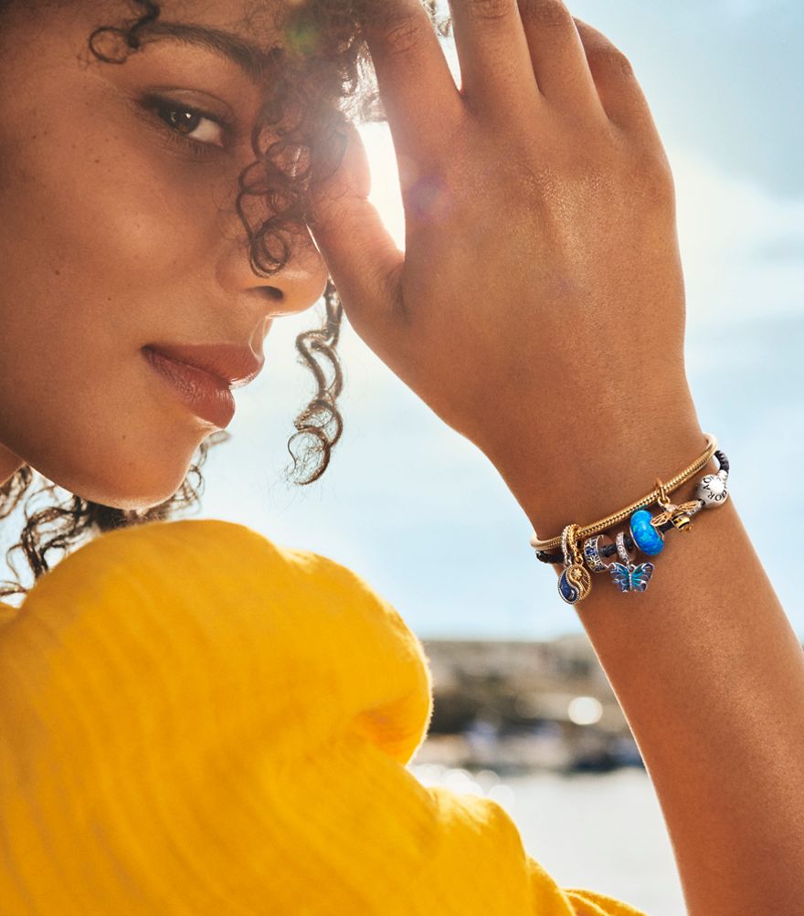 Smiling woman with colourful blue charms on bracelet.