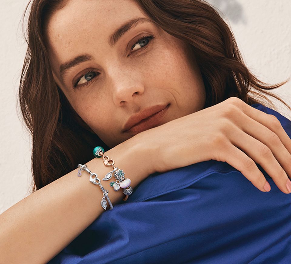Femme en robe bleu foncé portant deux bracelets à charms Pandora Moments