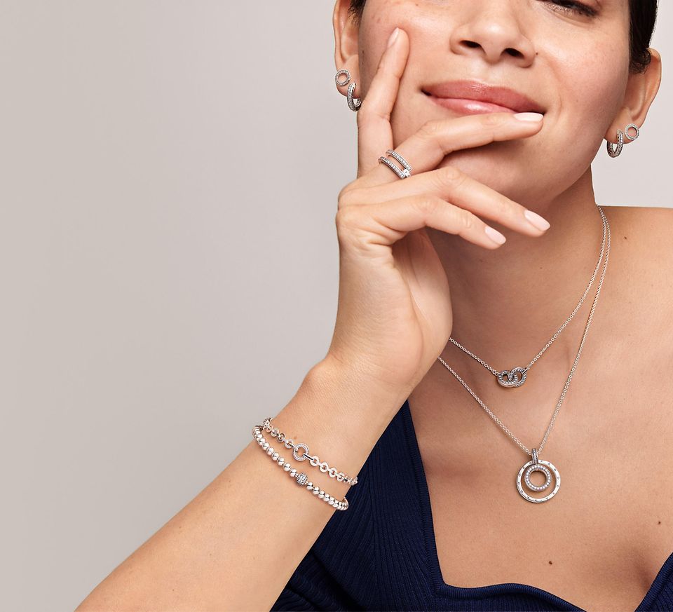 Woman wearing pandora signature stacking rings, bracelets, earrings and necklaces
