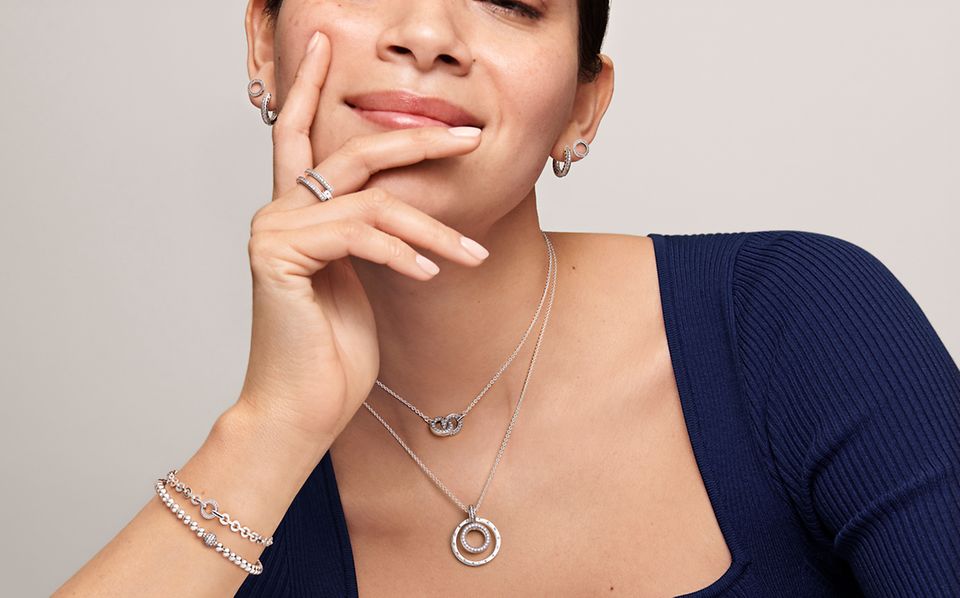 Vrouw met Pandora Signature-stapelringen, -armbanden, -oorbellen en -kettingen