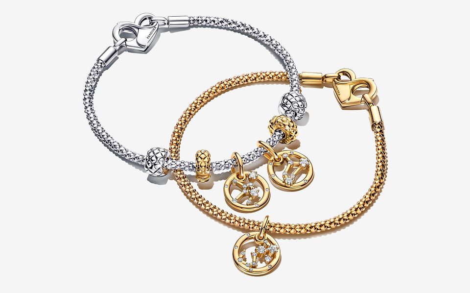 Image of a gold pandora moments zodiac charm bracelet on top of a silver bracelet