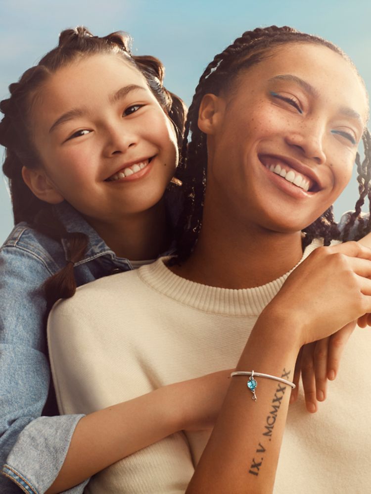 Córka przytulająca od tyłu matkę, która nosi bransoletkę UNICEF.