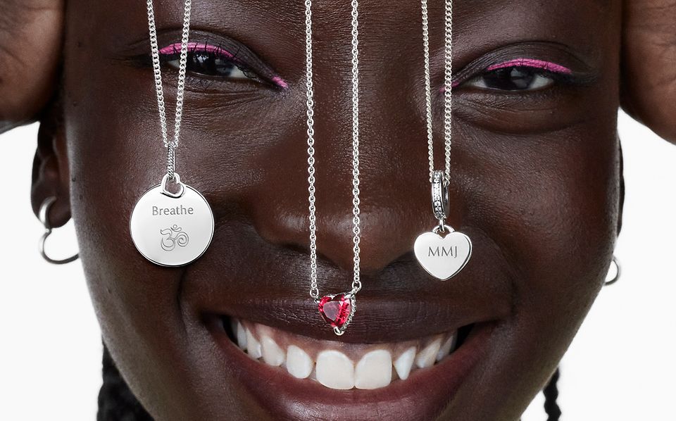Woman smiling with three silver Pandora necklaces dangling over her face