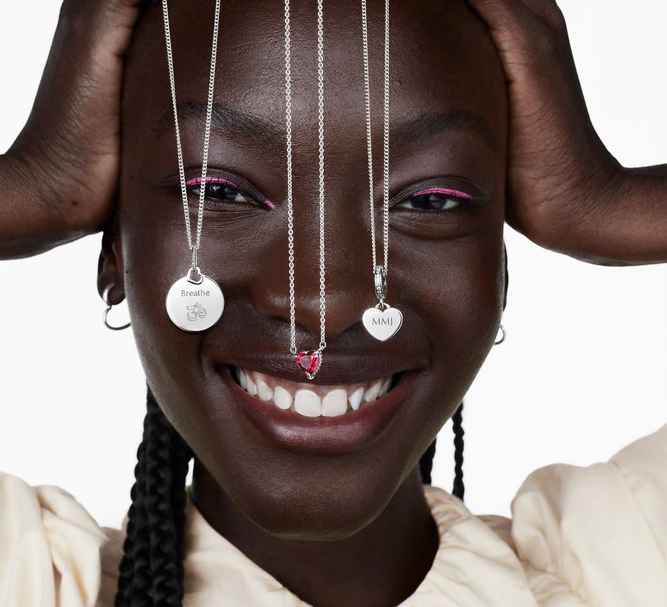 Femme souriante avec trois colliers Pandora en argent devant son visage